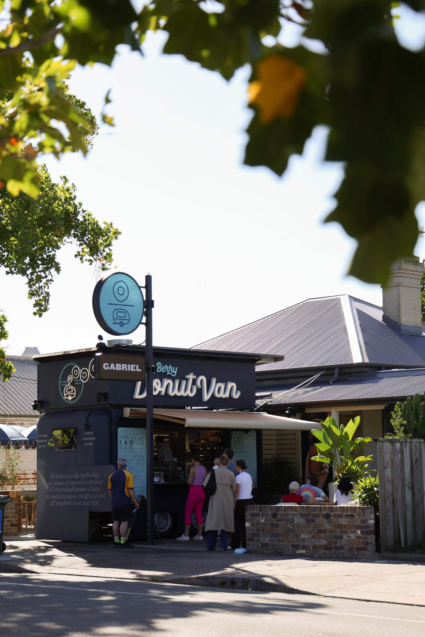 The van and its teal donut sign seen from across Queen Street under the plane trees