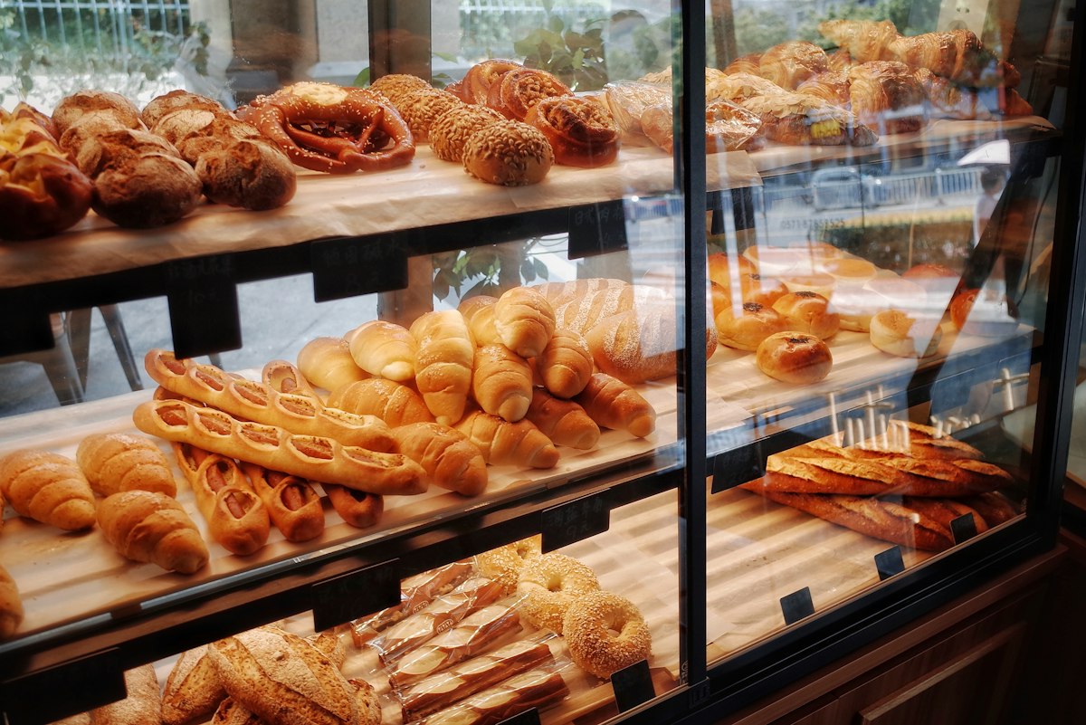 A bakery display cabinet piled high with fresh pastries, rolls and loaves