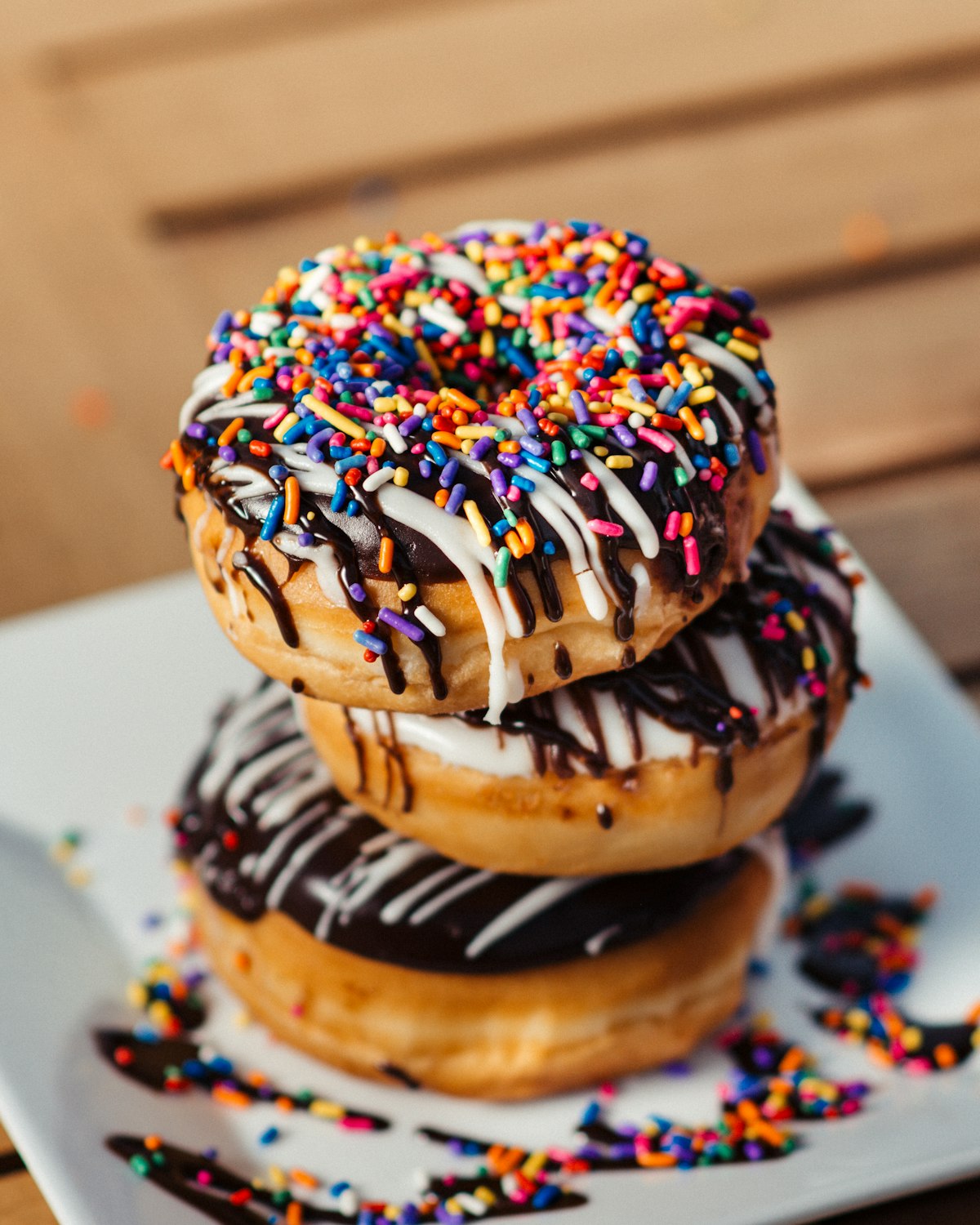 A stack of iced donuts covered in rainbow sprinkles