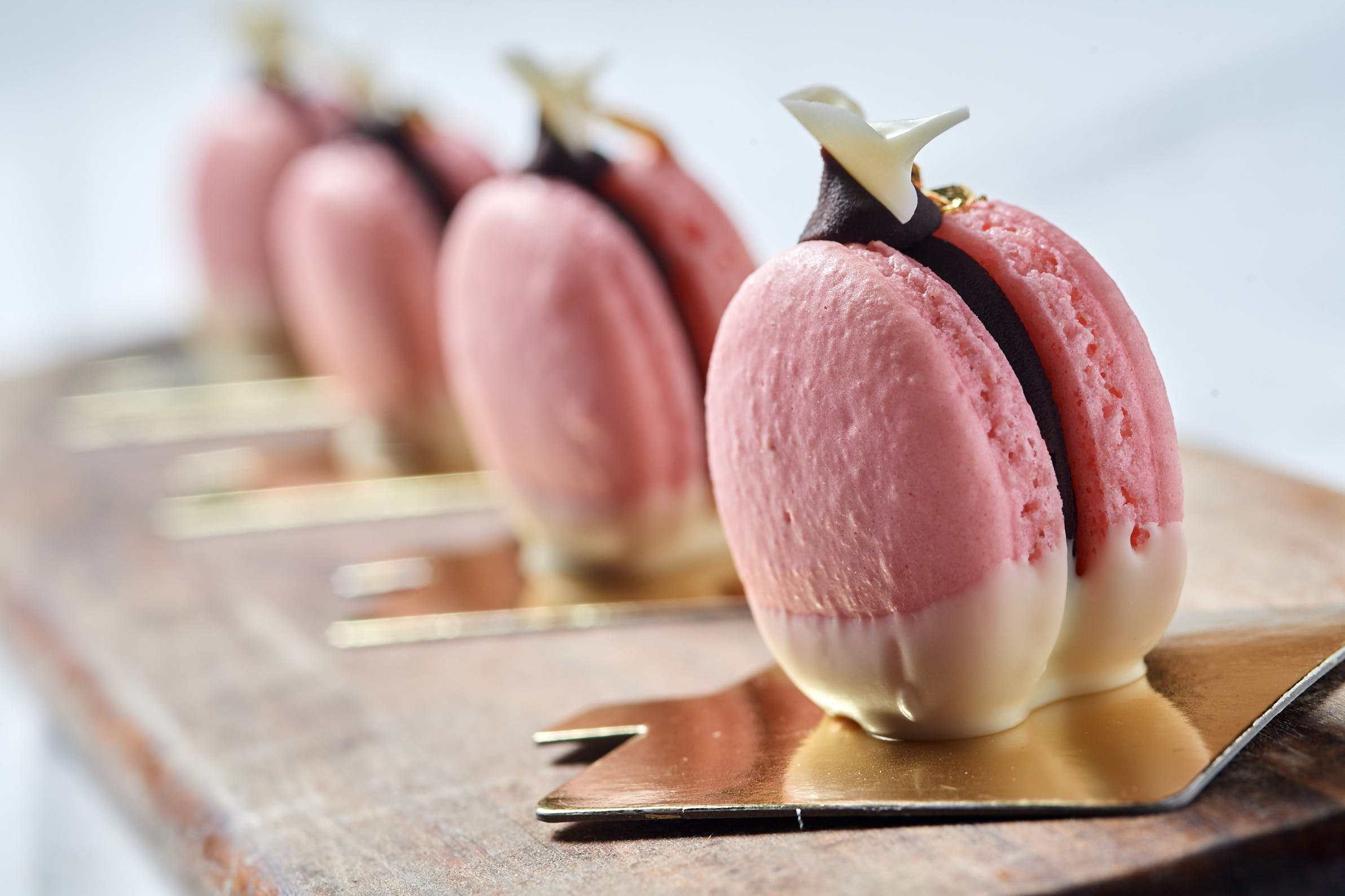 Metro's pink macaron petit fours lined up on gold boards