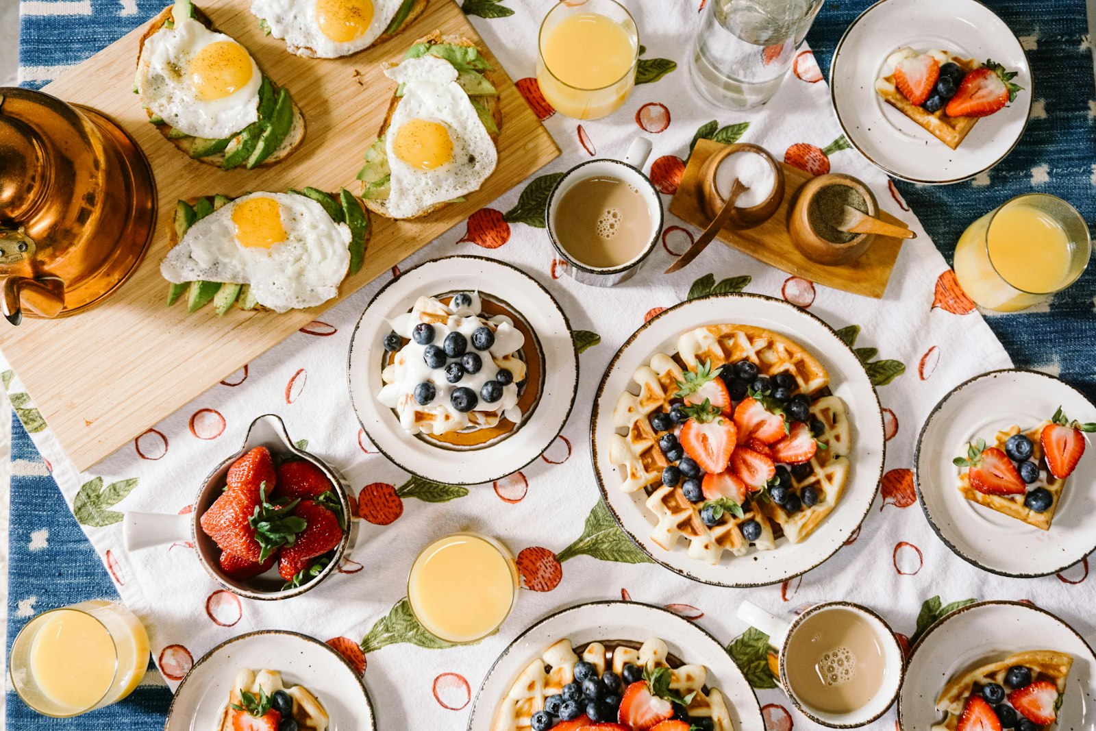 A shared brunch table with eggs, waffles, coffee and juice