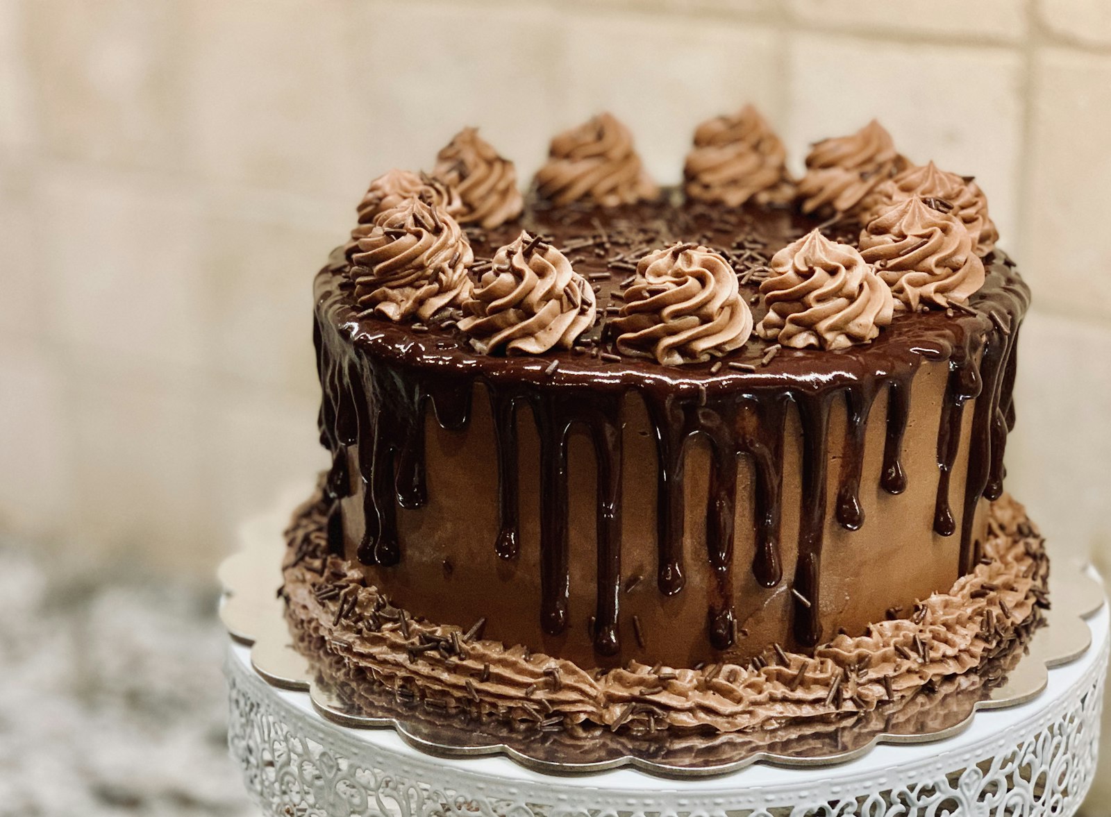A chocolate drip cake from the Pepys cake cabinet, on a vintage cake stand