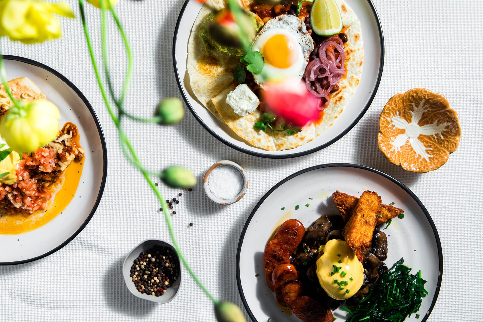 Three Turret breakfast plates on a white linen tablecloth with fresh flowers