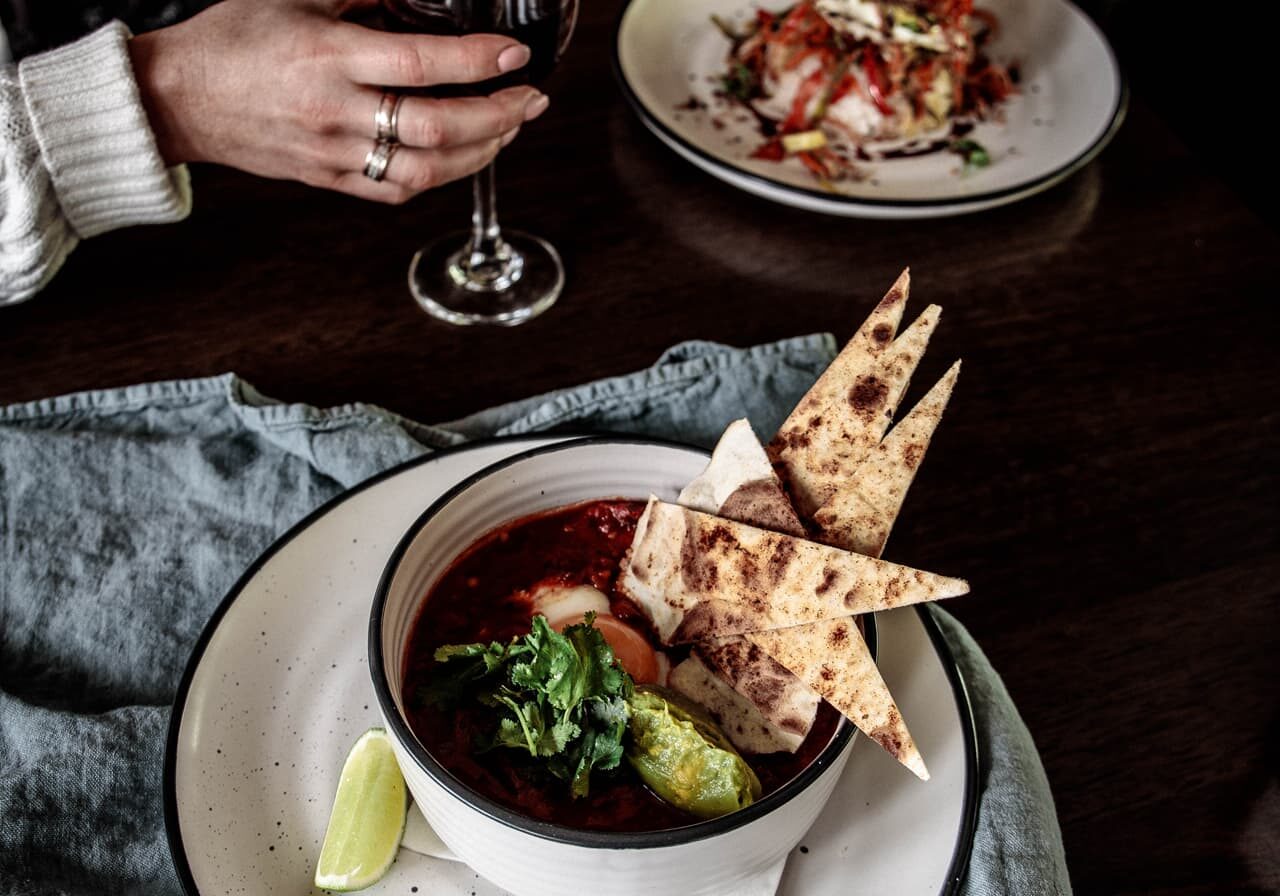 A Turret Cafe table — Tuscan bean braise with Bakehouse flatbread and a glass of local red wine